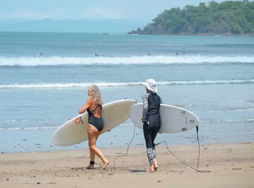 Dos mujeres saliendo a surfear con sus tablas de surf.